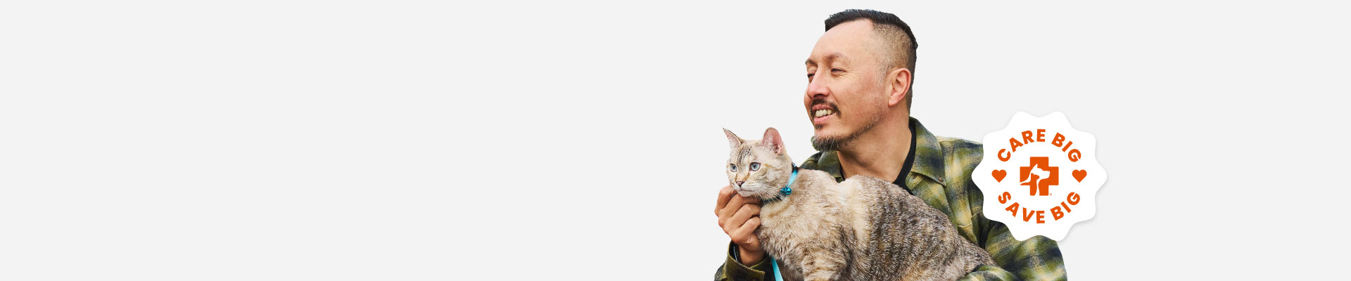A man holding a gray cat with a blue collar duing a photoshoot