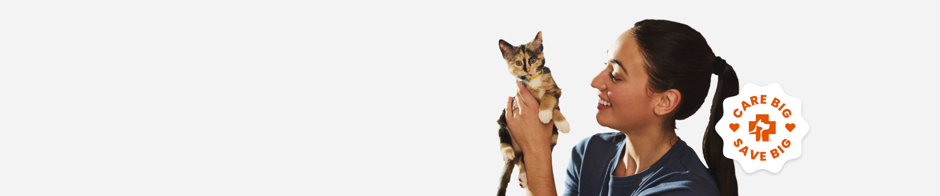 A woman holding a small kitten in her hands. With Care Big Save Big seal.